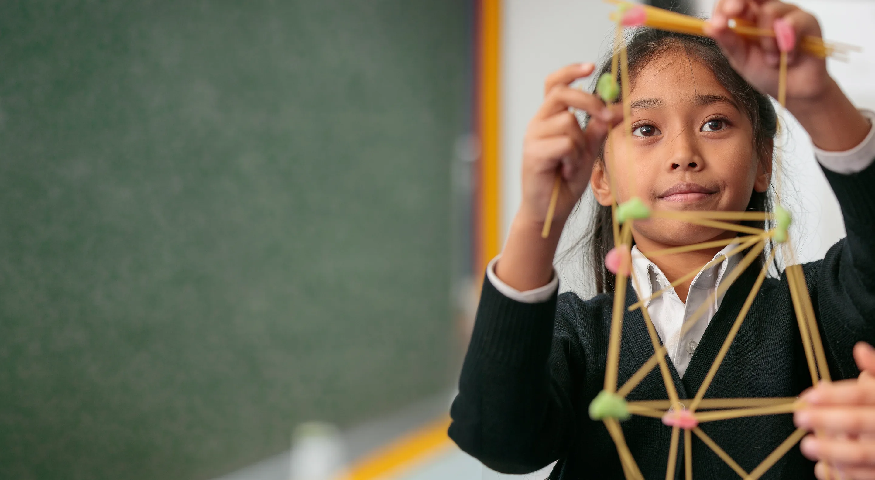 A primary student building a structure from spaghetti and gumdrops
