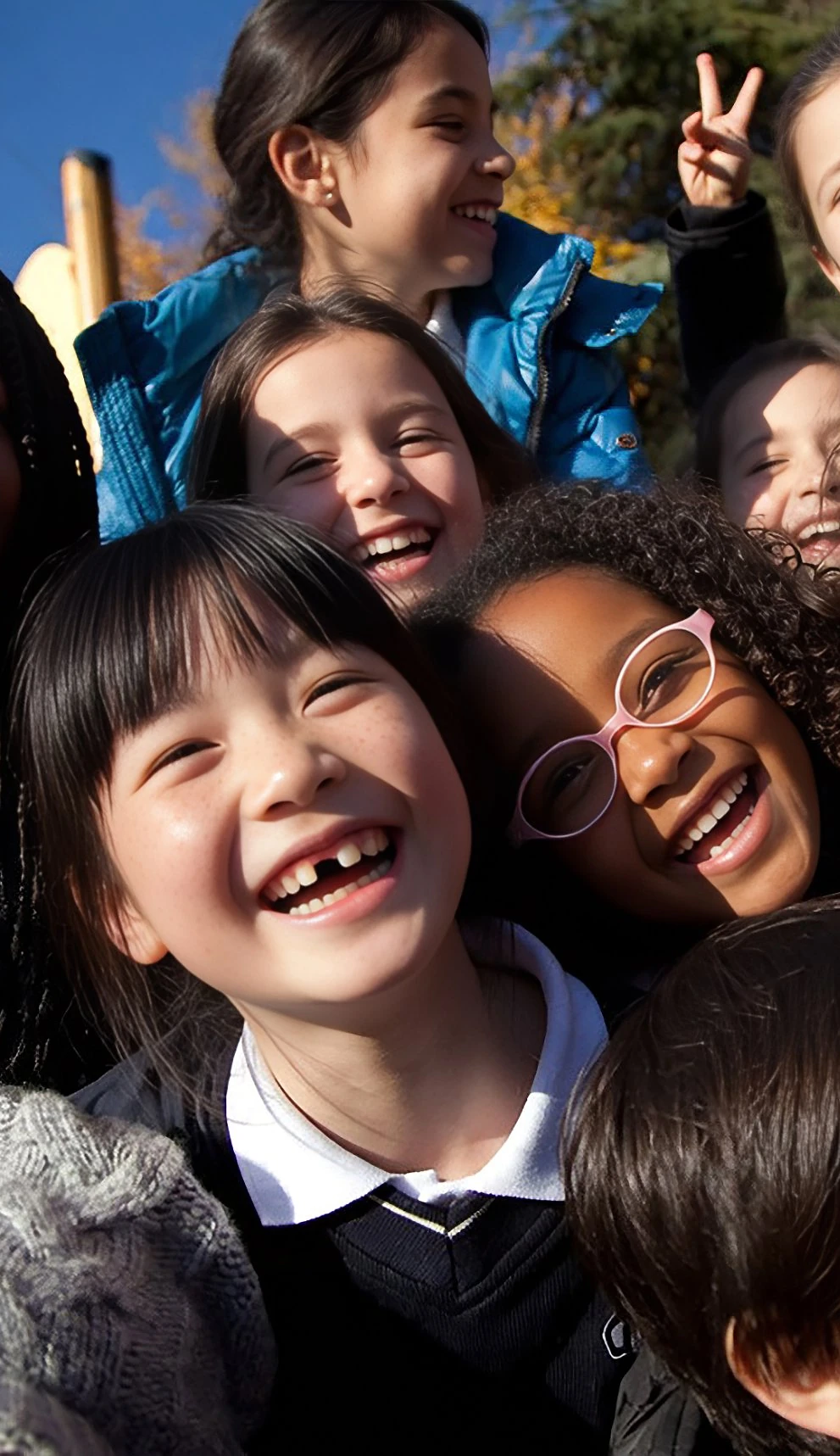A group of students laughing together in the playground on a sunny day